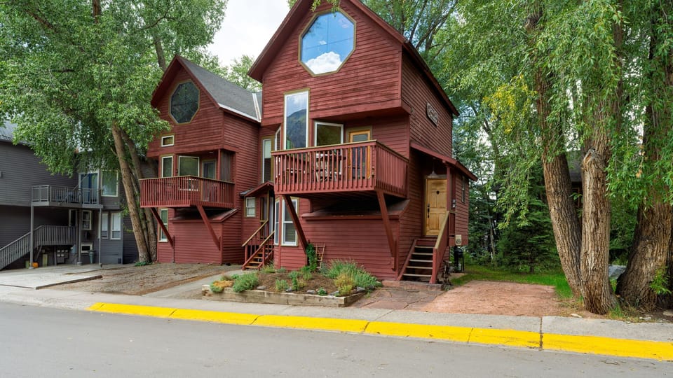 Stay in a distinctive red mountain home surrounded by mature trees and multiple outdoor spaces.