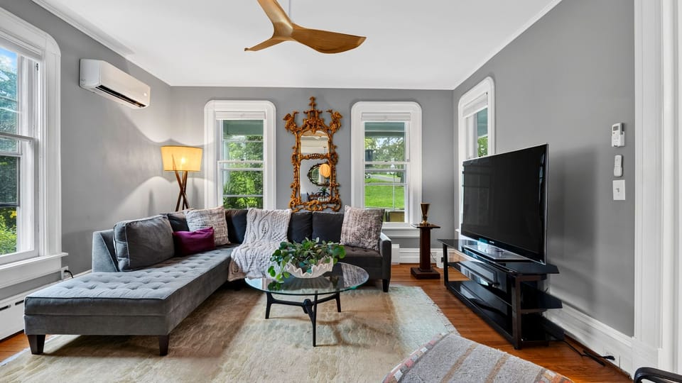 Sun-drenched living room featuring hardwood floors, a fireplace, and comfortable traditional seating.