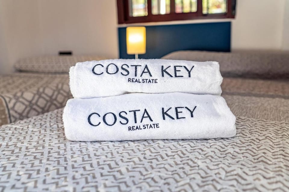 Bed, Property logo or sign, Photo of the whole room, Logo/Certificate/Sign, Bedroom, Text overlay, Certificate/Award, towels