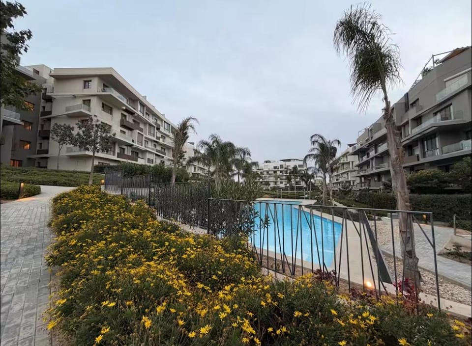A luxurious bedroom and a cozy living area with a stunning view of the swimming pool Apartment in New Cairo City