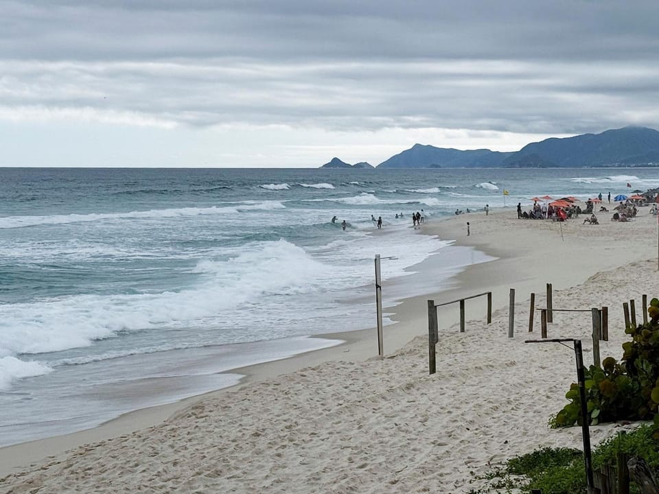 Feet in the sand with a king bed and balcony with Apartment in Rio de Janeiro