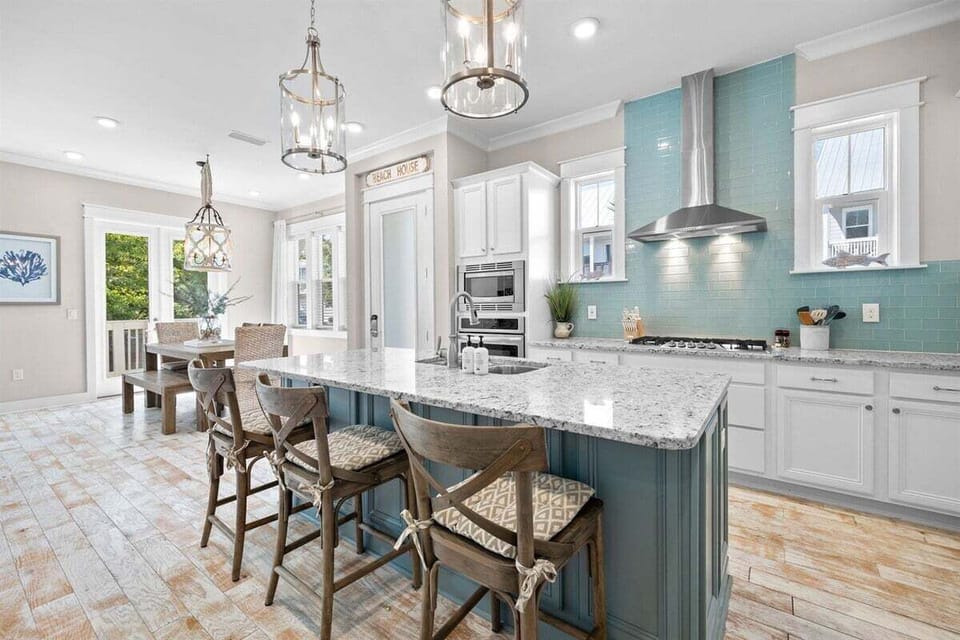 A beautifully designed kitchen with white cabinetry, a blue tile backsplash, and high-end appliances.