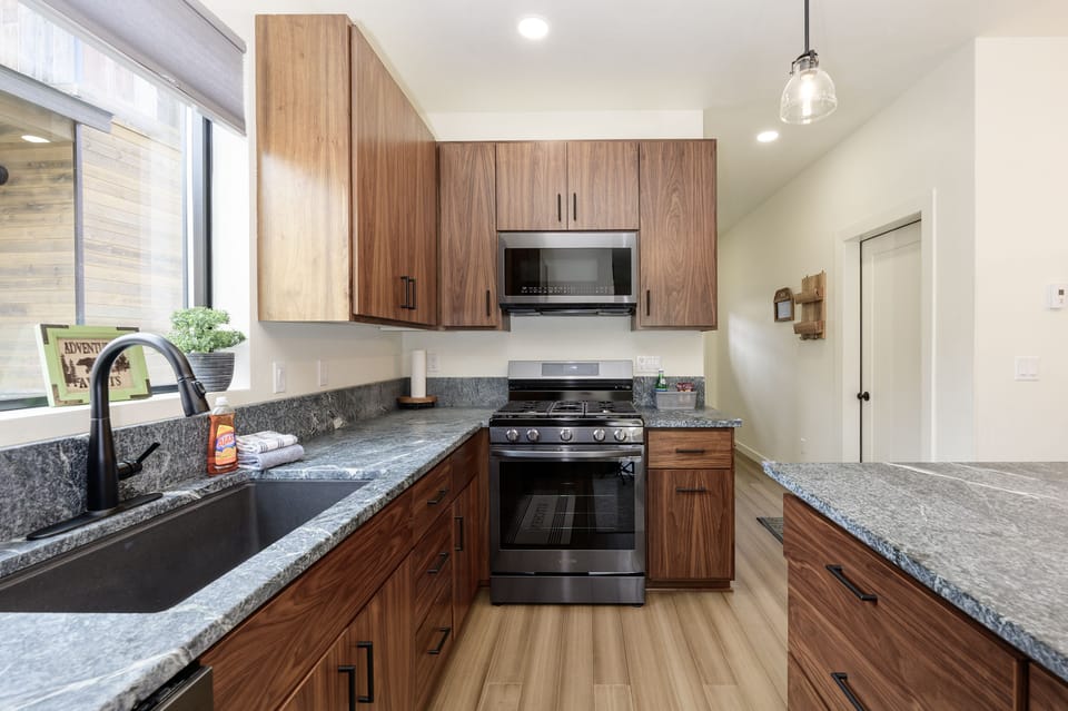 - Sleek kitchen design with stainless steel oven and ample counter space   - Wood cabinets and natural light enhance the modern cooking experience   - Open layout keeps the kitchen connected to the rest of the home life