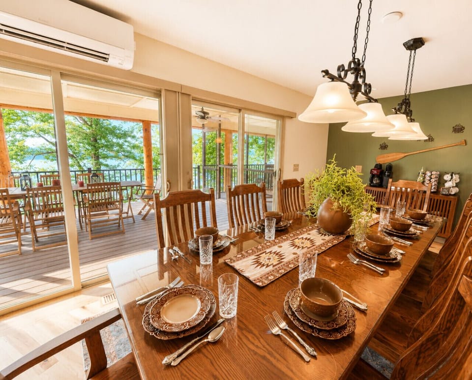 Elegant lakeview dining space with seating for large groups, rustic-modern décor, and seamless access to a spacious outdoor deck for unforgettable gatherings.