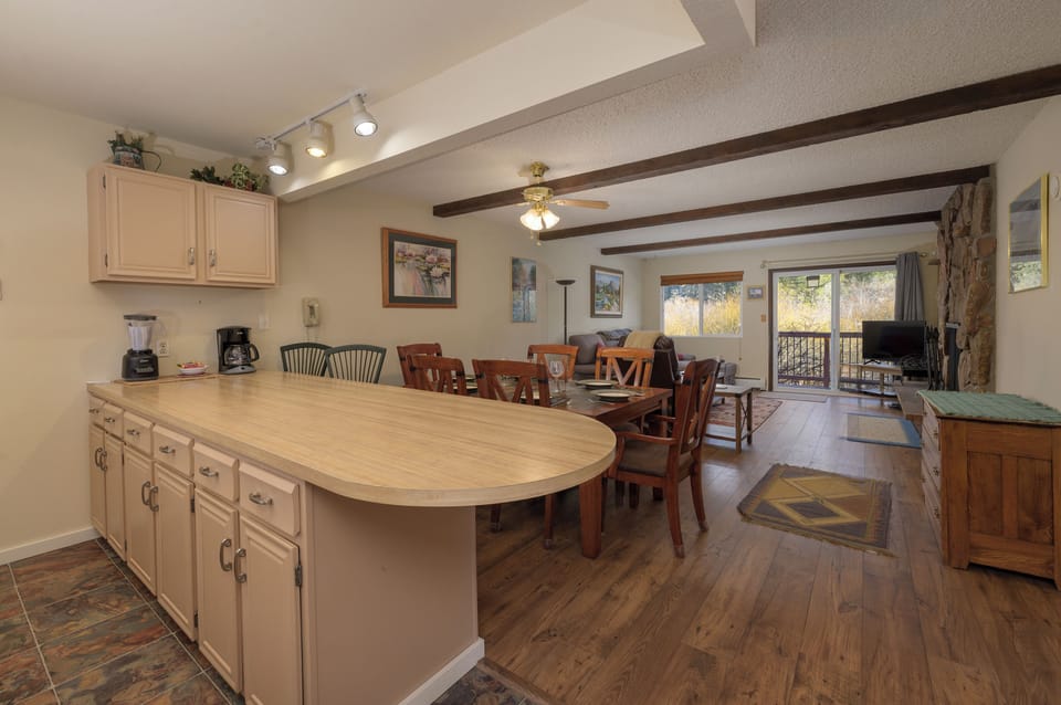 Your open-plan kitchen and living space flows seamlessly together, featuring warm wood beams overhead and rich hardwood floors underfoot.