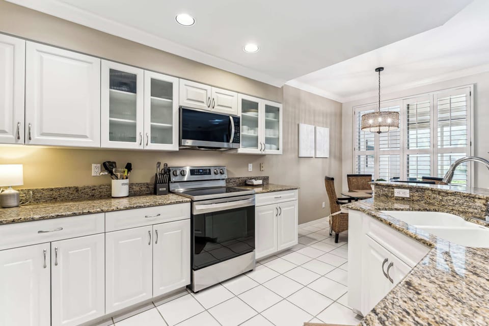 The kitchen has granite counters, clean appliances and white cabinets
