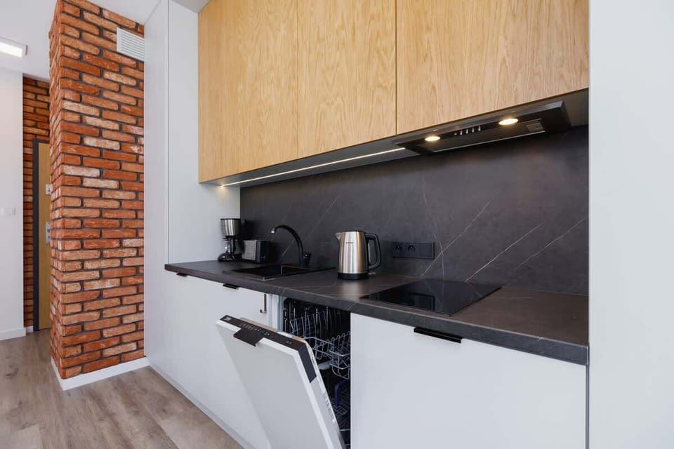 Another perspective of the kitchen area, showing its integration with a small dining space and open dishwashing. 