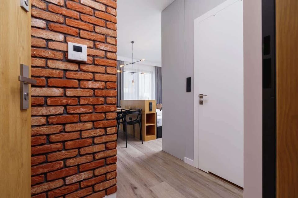 A continuation of the brick wall design in a hallway, featuring a door and light flooring