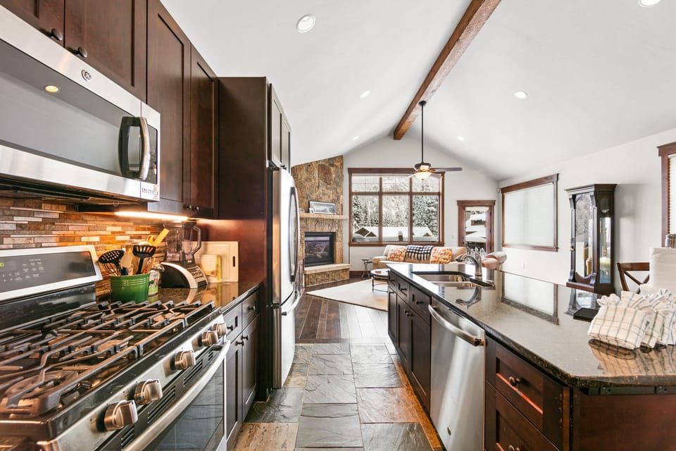Your gourmet kitchen features rich wood cabinetry, stone floors, and modern appliances perfect for creating memorable mountain meals.