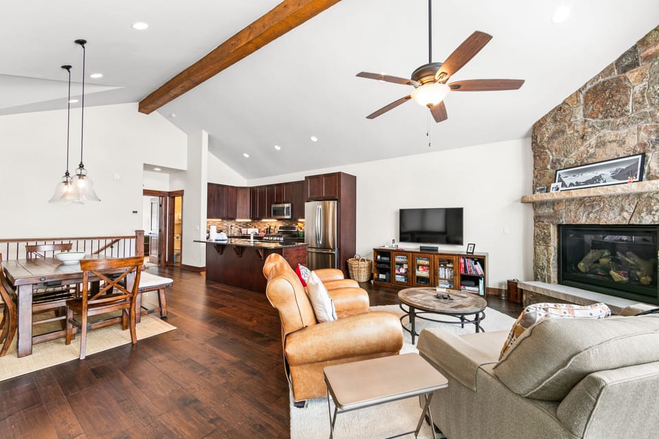 Relax in your open-concept living space with exposed beams, stone fireplace, and modern kitchen—perfect for gathering after mountain adventures.