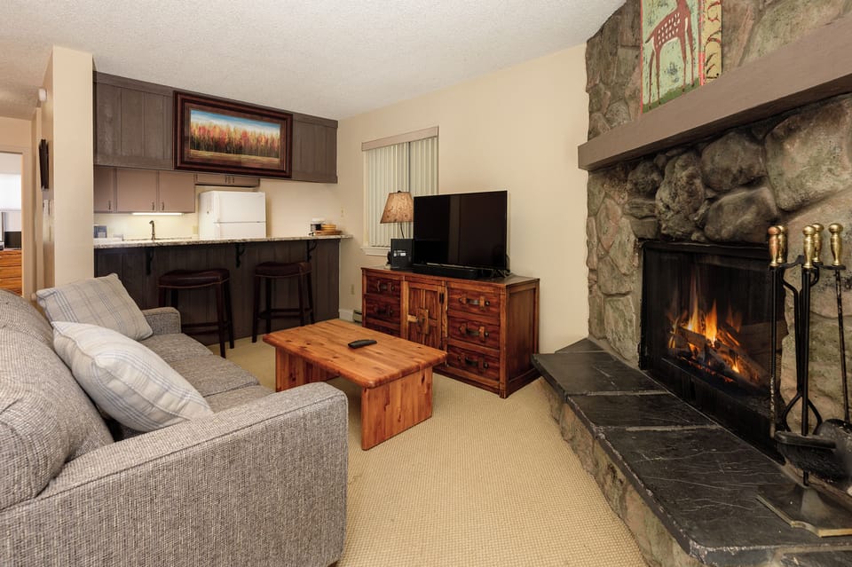 Cozy up by your crackling stone fireplace after mountain adventures, with a fully equipped kitchen and plush seating for ultimate relaxation.