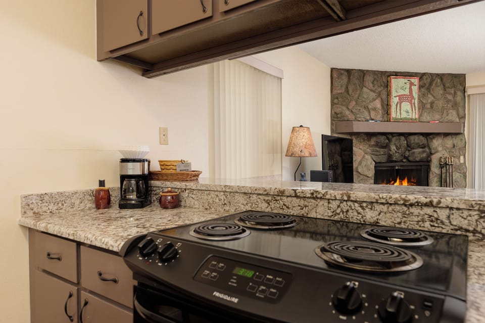 Your fully equipped kitchen features granite counters and overlooks the cozy living area with stone fireplace.