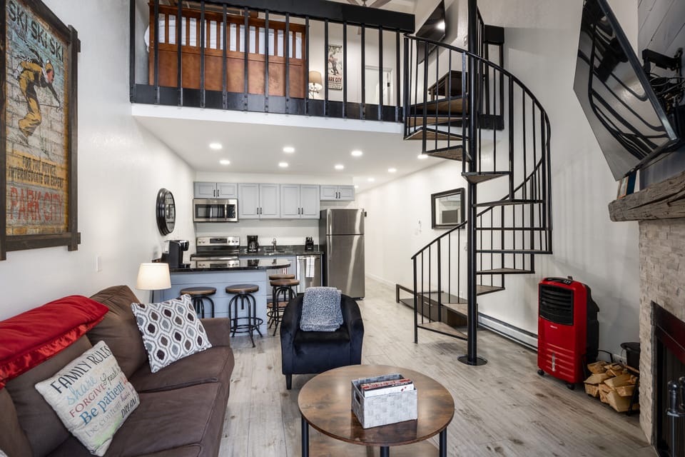 - Stylish living space with open kitchen and spiral staircase  
- Modern appliances and bar seating perfect for gatherings  
- Loft bedroom overlooks cozy living area with fireplace