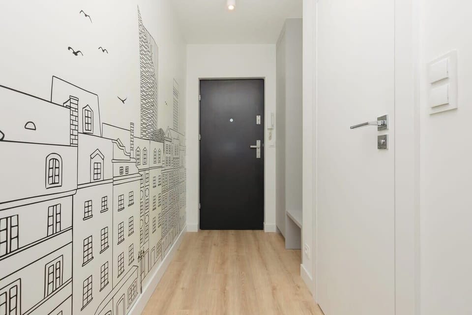 A hallway with a creative black-and-white city mural, leading to the apartment entrance.
