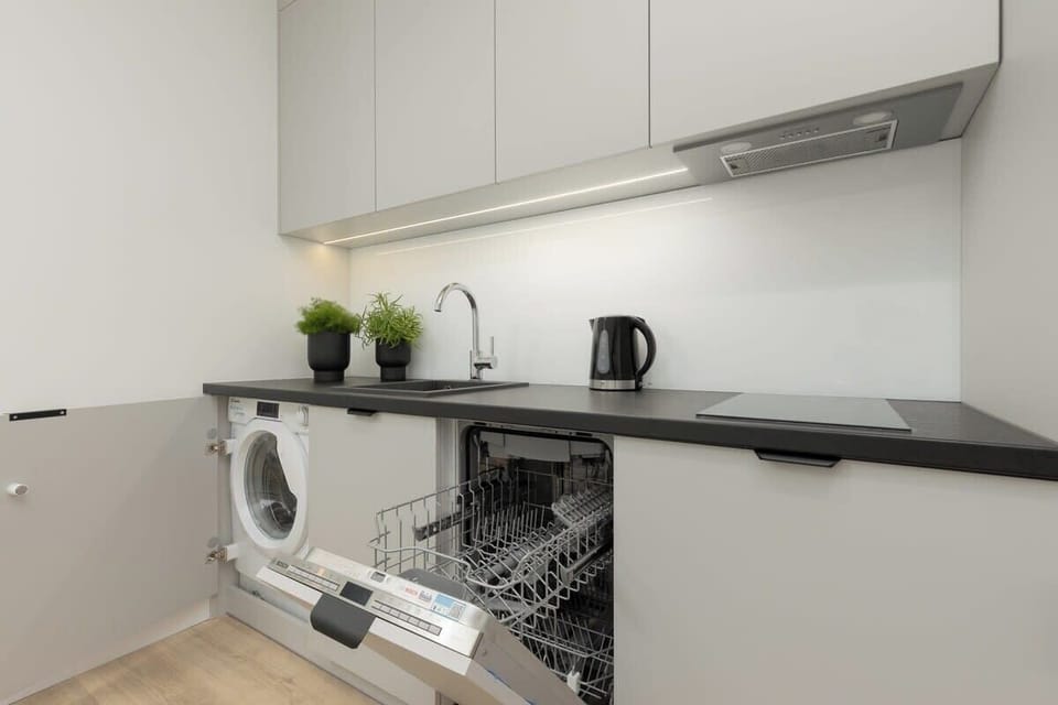 A functional kitchen space with a built-in washing machine and under-cabinet lighting.
