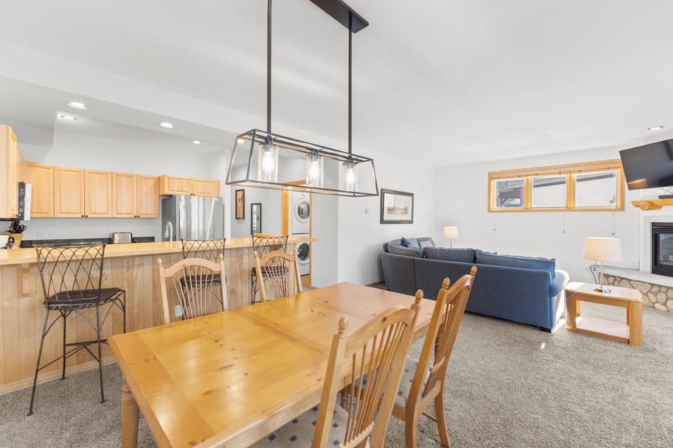 Relax in your spacious open-plan living area where natural wood accents and modern lighting create the perfect mountain retreat atmosphere.