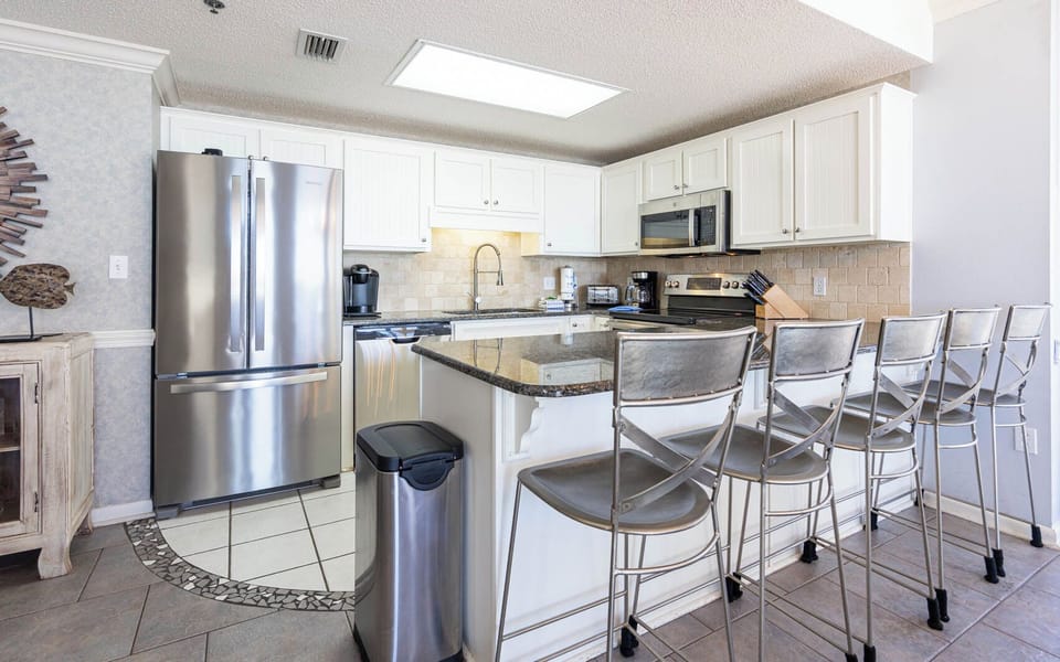 Kitchen features sleek stainless appliances, Keurig, coffee maker, and a spacious breakfast bar with seating