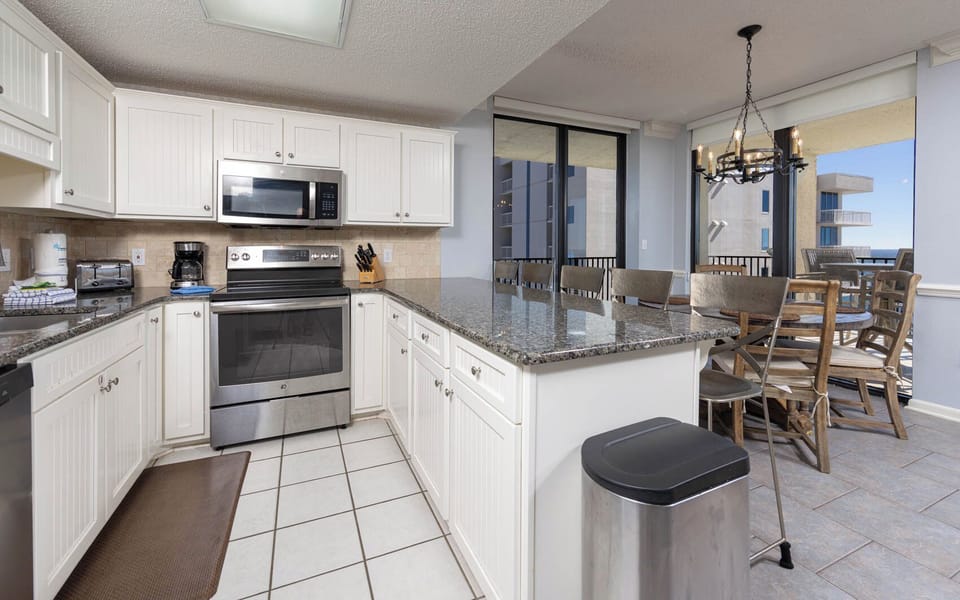 White cabinetry complements the granite countertops and stainless appliances in this kitchen, featuring a breakfast bar