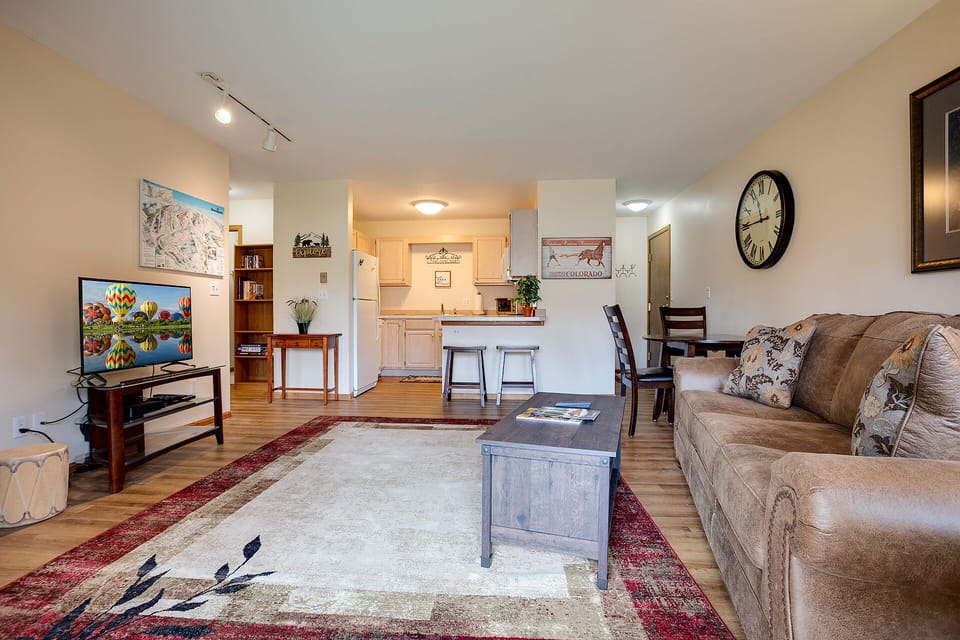 Settle into this welcoming open-plan space where warm wood floors meet comfortable seating, perfect for your mountain getaway relaxation.