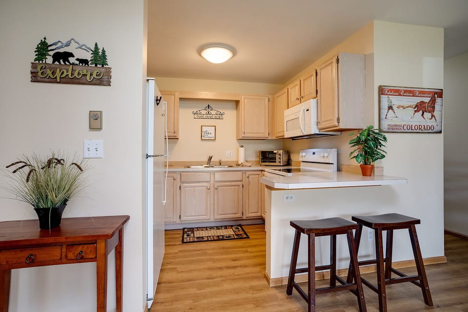 Your fully equipped kitchen awaits with warm wood cabinets, modern appliances, and a breakfast bar where you can enjoy your morning coffee.