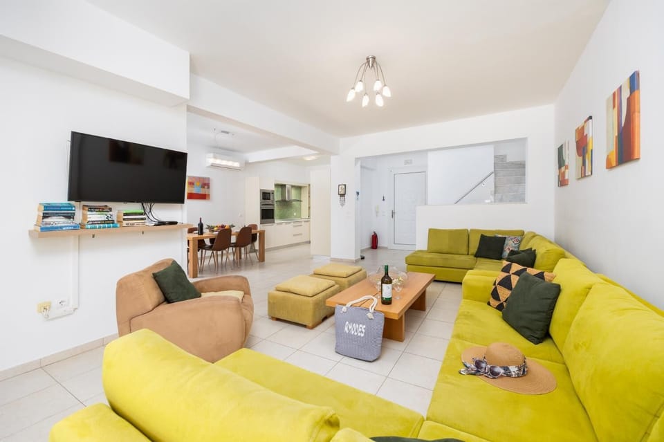 Open-plan living room with sofas, dining area, kitchen, A/C, WiFi internet, and satellite TV