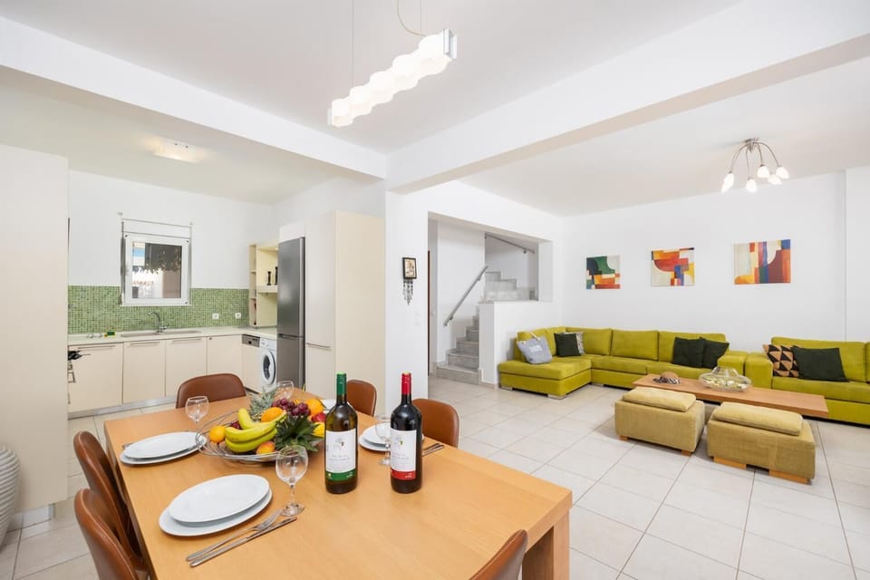 Open-plan living room with sofas, dining area, kitchen, A/C, WiFi internet, and satellite TV