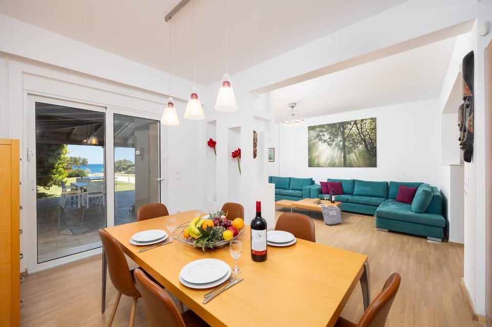 Main building: open-plan living room with sofas, dining area, kitchen, ornamental fireplace, A/C, WiFi internet, satellite TV, and sea views