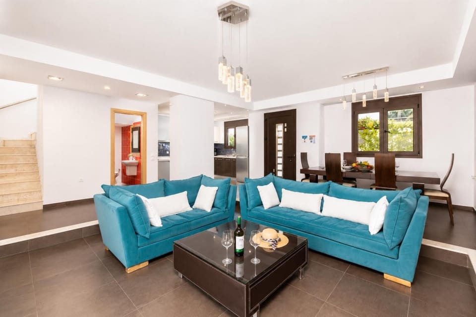Open-plan living room with sofas, dining area, kitchen, ornamental fireplace, A/C, WiFi internet, satellite TV, and sea views