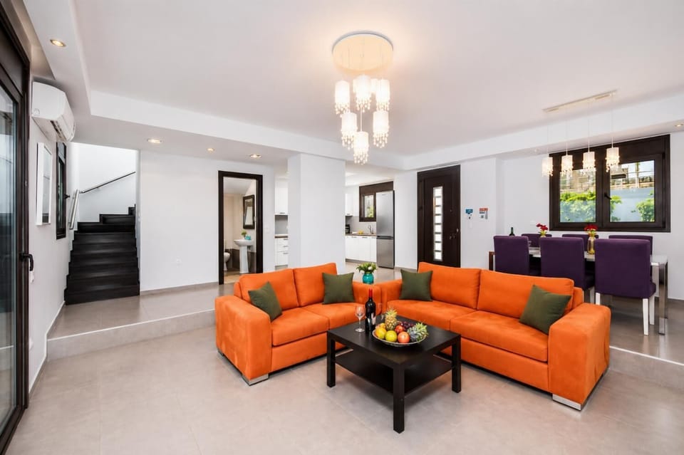 Open-plan living room with sofas, dining area, kitchen, ornamental fireplace, A/C, WiFi internet, satellite TV, and sea views
