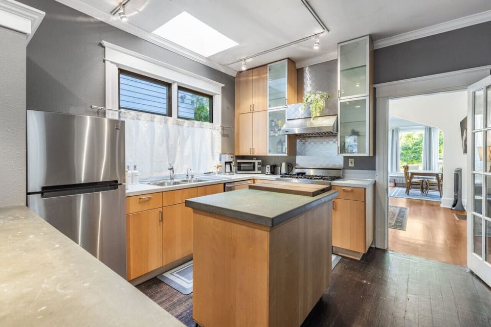 Kitchen with center island, microwave, oven, refrigerator, and more appliances and supplies.