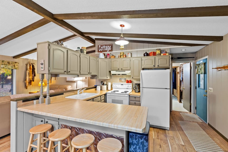 Step into this charming cottage-style kitchen, featuring warm wood accents, a full-sized refrigerator, and a convenient electric stove.