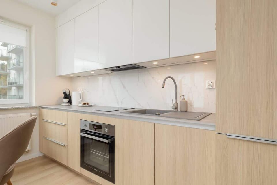 A modern kitchen with white cabinets, wooden accents, and built-in appliances.
