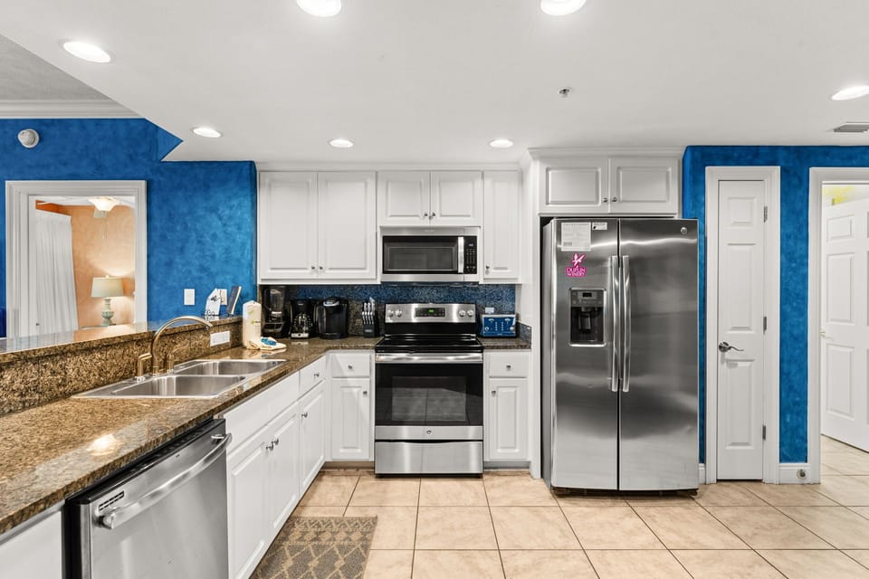 Your fully equipped kitchen features granite counters, stainless appliances, and vibrant blue walls that create a cheerful cooking space.