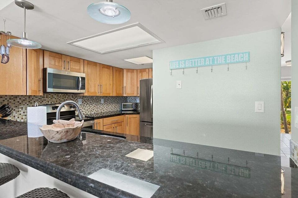 The wide granite counter provides additional preparation space and a convenient serving area beside the fully equipped kitchen.