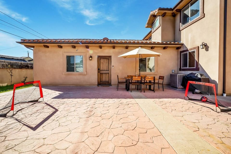 Front door entrance with private outdoor dining area, bbq grill, soccer nets, large space, all nestled behind a private gate.