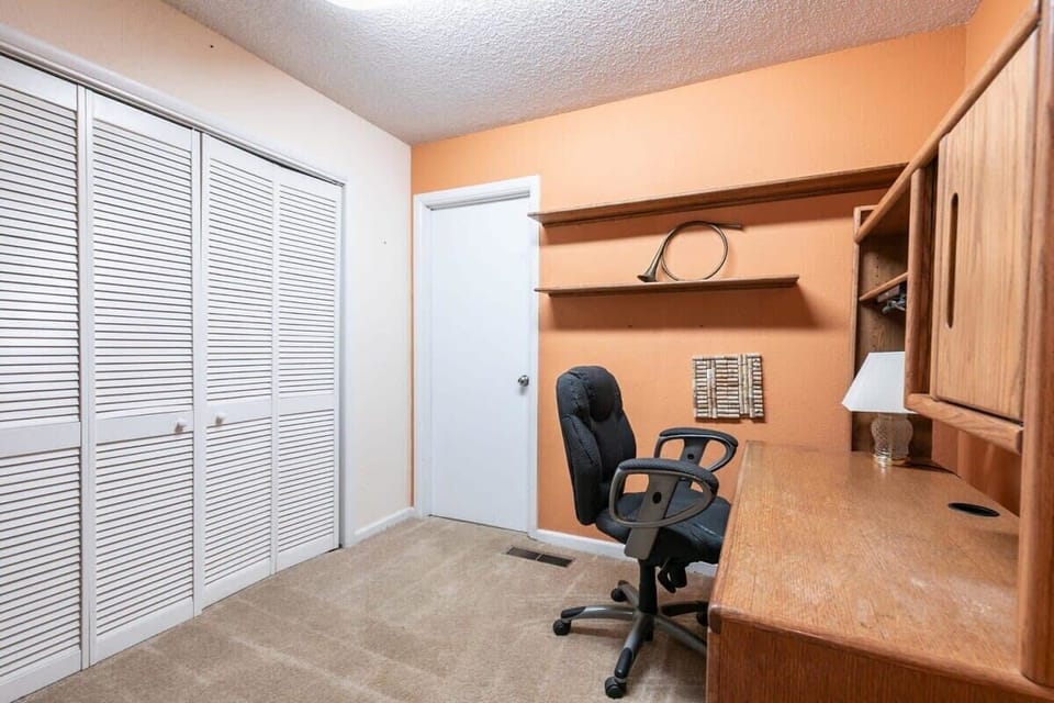 A spacious downstairs office provides a quiet space to catch up on remote work needs with a large desk and office chair.