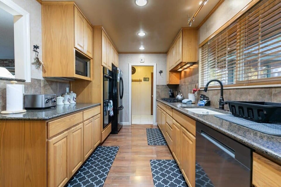 The kitchen has two entry points, one from the front entryway and the other from the open living/dining room.