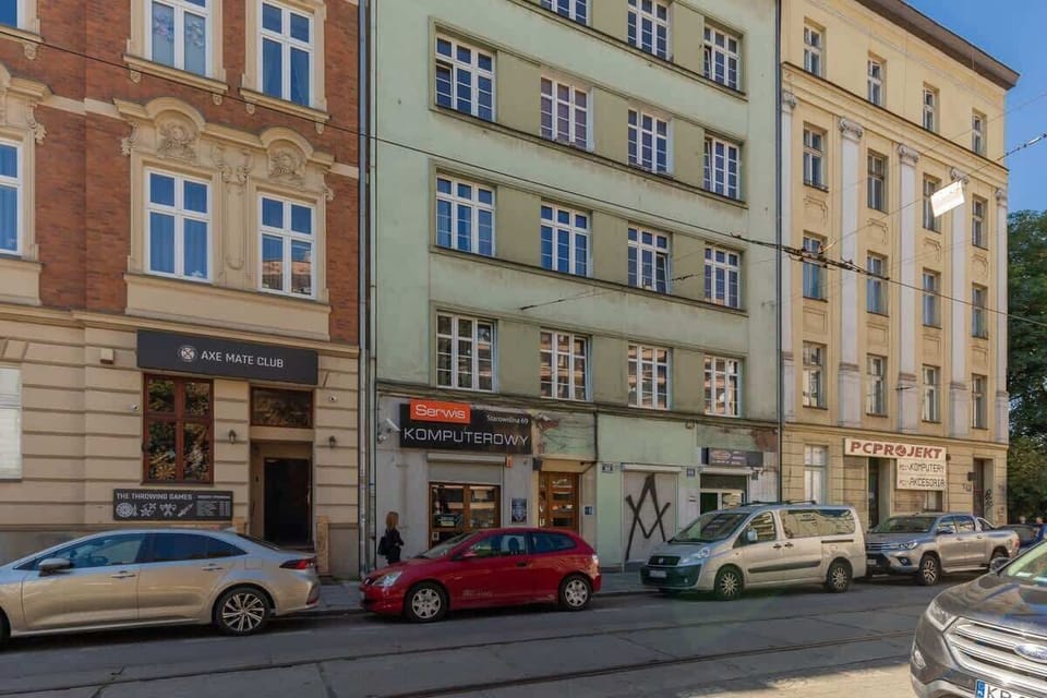 An exterior street view featuring historic buildings with colorful facades, local shops, and parked cars, capturing the lively urban neighborhood.






