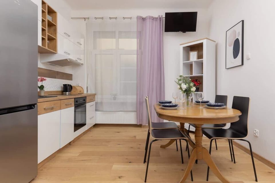 A spacious kitchen and dining area with white cabinets, wooden countertops, and modern appliances, offering a bright and functional layout.
