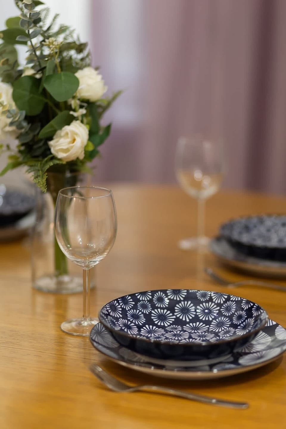 A close-up of a beautifully set dining table with elegant plates, glassware, and fresh flowers, enhancing the dining ambiance.

