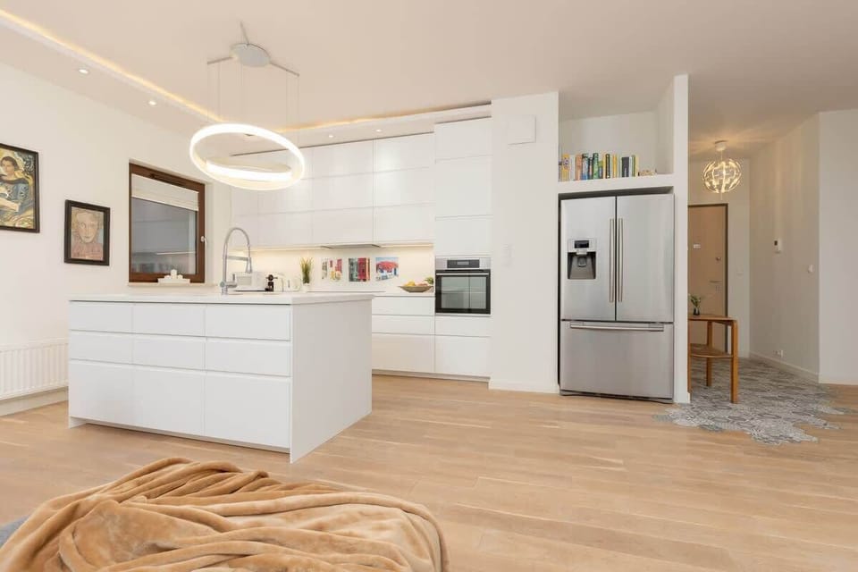 A large open kitchen with white cabinetry, an island, and modern lighting fixtures.
