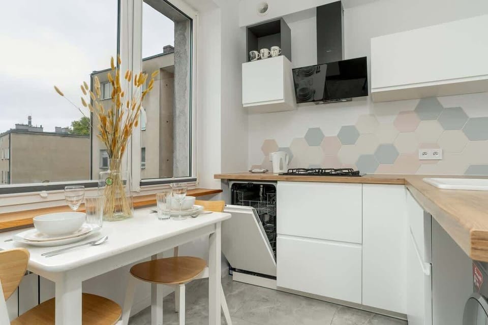 Another angle of the kitchen, highlighting the modern white cabinets, wooden countertop, and stylish backsplash.
