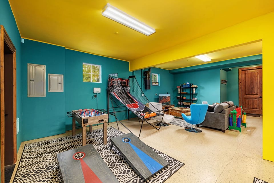 Heated game room, featuring, foosball, ping pong, pop-o-shot, corn hole, connect four, sitting area with a large TV, a perfect haven for lively gatherings and relaxed evenings