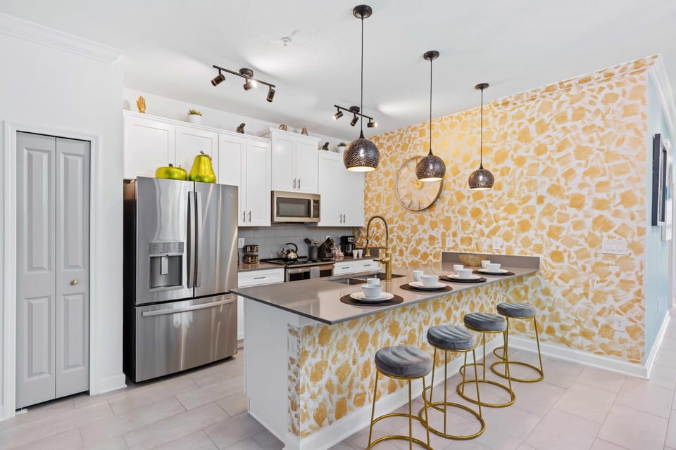 Discover our stylish open-concept kitchen, boasting ample natural lighting and featuring a countertop table with chairs, perfect for casual dining or gathering.