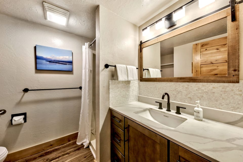 Unwind in your beautifully appointed bathroom featuring warm wood accents, elegant marble countertops, and modern fixtures for a luxurious retreat.