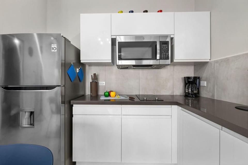 Fully equipped kitchen: Fridge, microwave, coffee maker and sleek countertops.