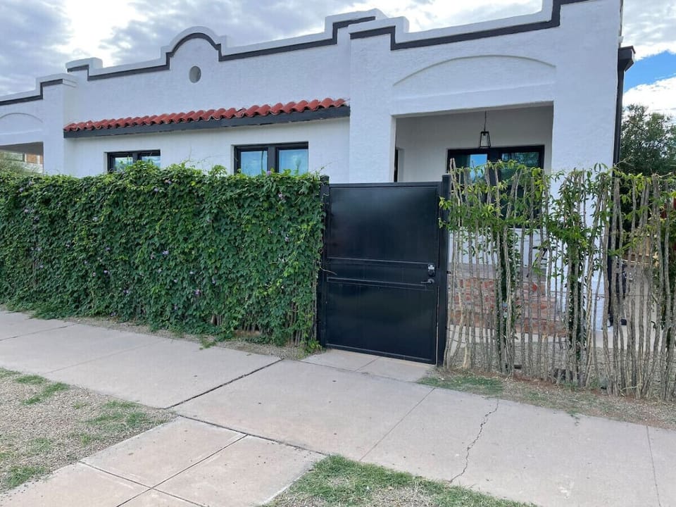 Front of duplex with private courtyard, beautiful ocotillo fencing with flowering vines, and steel gate with coded lock for secure entry