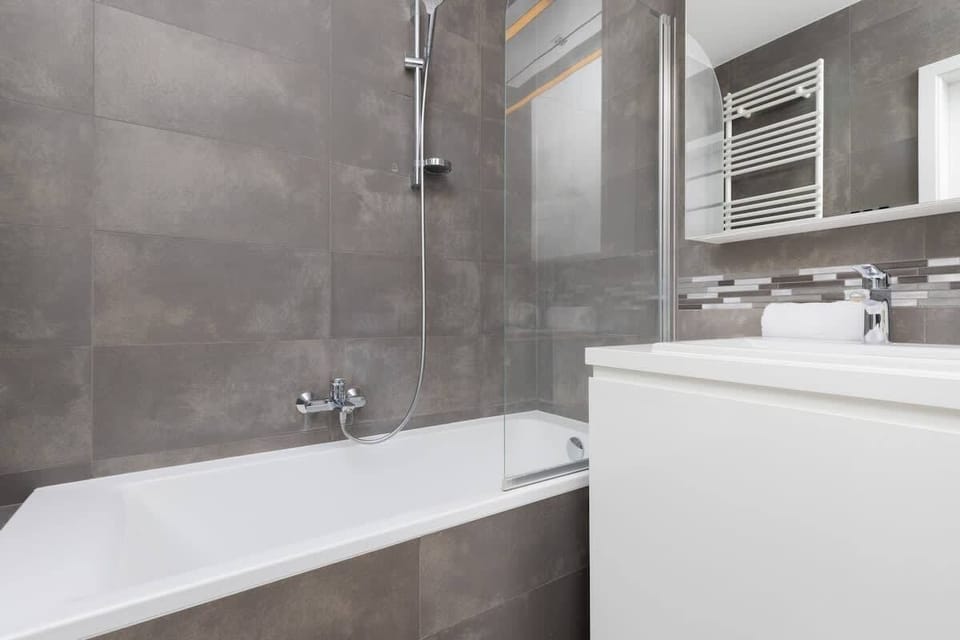 Modern bathroom with grey tiles and bath.