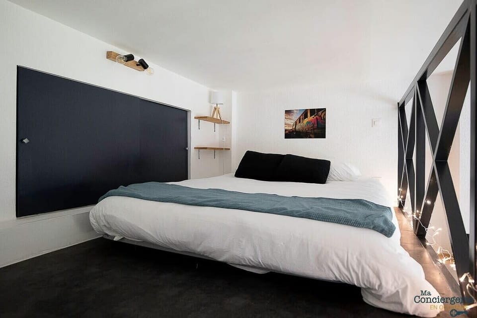 Coin nuit en mezzanine, accessible par une échelle avec lit double et placard.