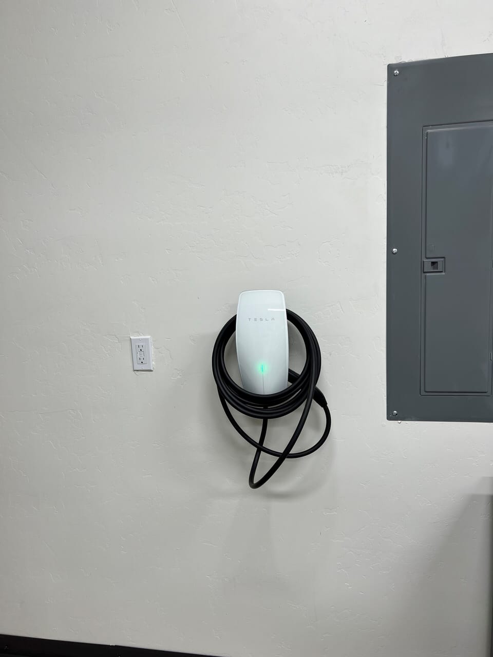 Tesla Universal wall connector for charging Tesla (NACS plug) and non-Tesla (J1772 plug) vehicles.